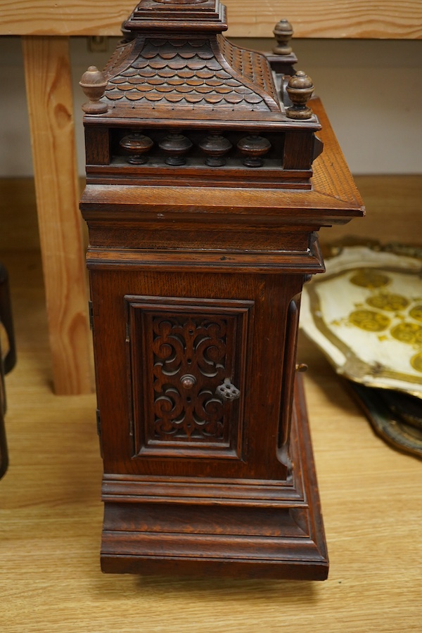 An early 20th century carved oak mantel clock, with key and pendulum, 58cm high